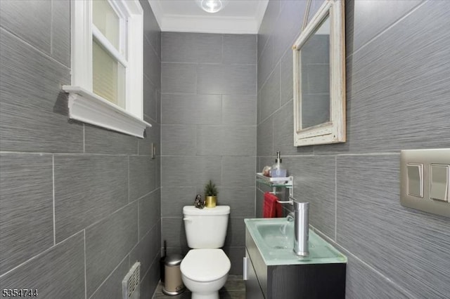 half bath with crown molding, tile walls, vanity, and toilet