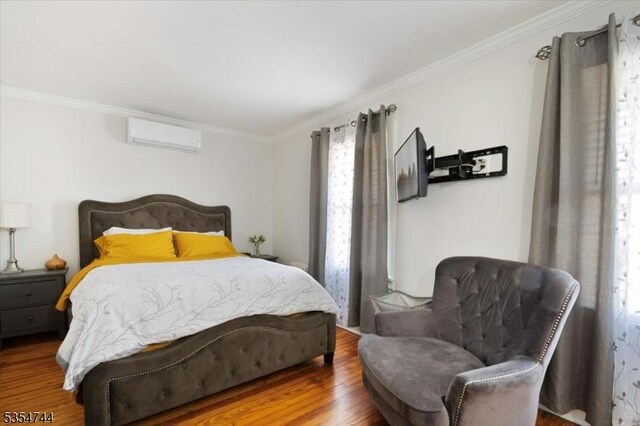 bedroom with crown molding, an AC wall unit, and wood finished floors