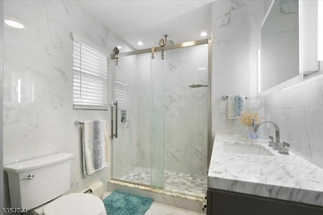 bathroom with vanity, toilet, a marble finish shower, recessed lighting, and tile walls