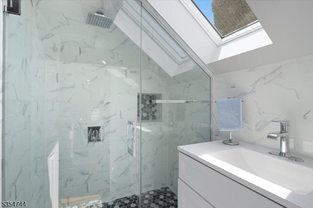bathroom featuring vanity, a marble finish shower, and a skylight