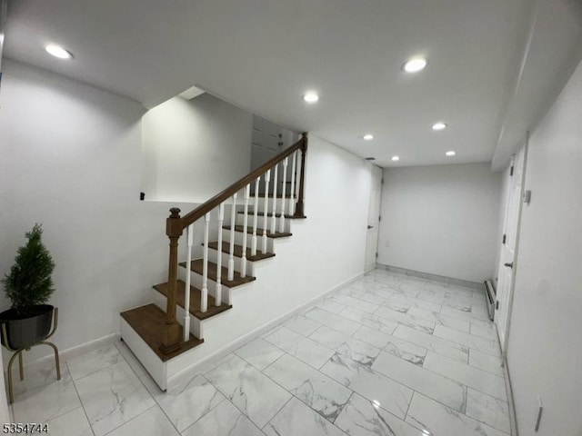 finished below grade area featuring stairway, baseboards, recessed lighting, and marble finish floor