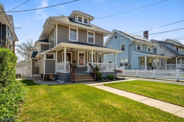 american foursquare style home featuring a porch, central AC, fence, and a front yard