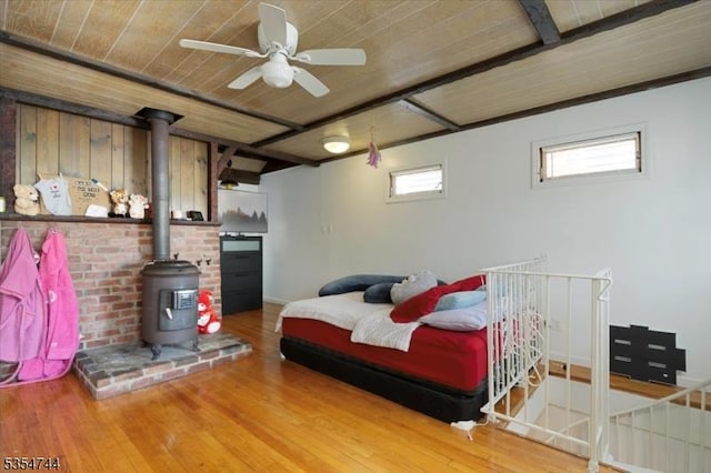 bedroom featuring wooden ceiling, a wood stove, and wood finished floors