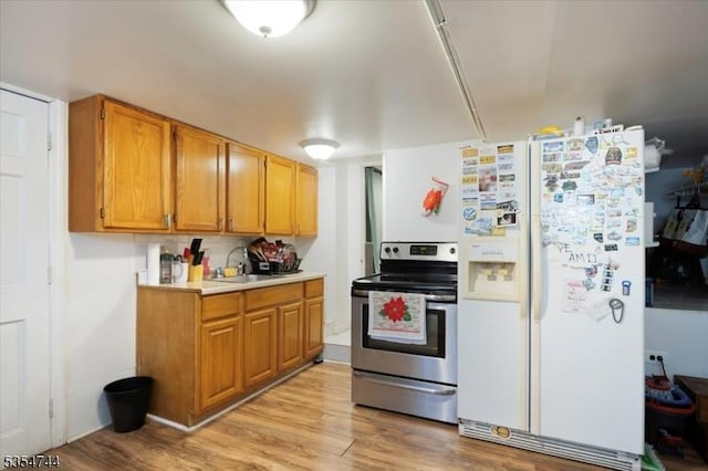 kitchen with light countertops, a sink, light wood finished floors, stainless steel electric stove, and white fridge with ice dispenser