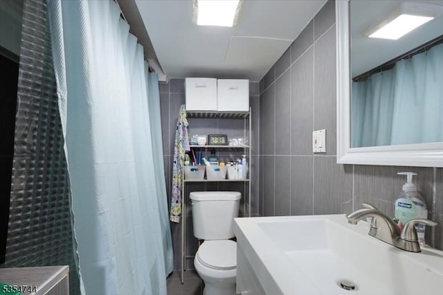 full bath with a sink, tile patterned floors, toilet, and tile walls