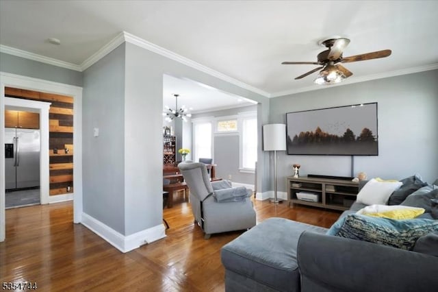 living room featuring baseboards, ornamental molding, ceiling fan with notable chandelier, and wood finished floors