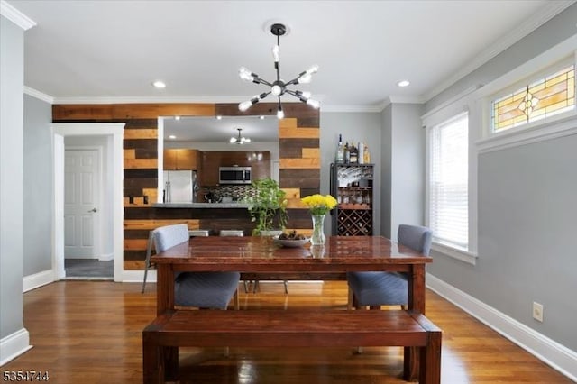 dining room featuring an inviting chandelier, baseboards, crown molding, and wood finished floors