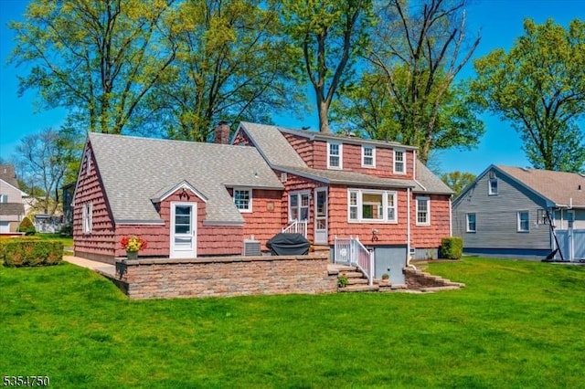 rear view of property featuring a shingled roof, a yard, and a chimney
