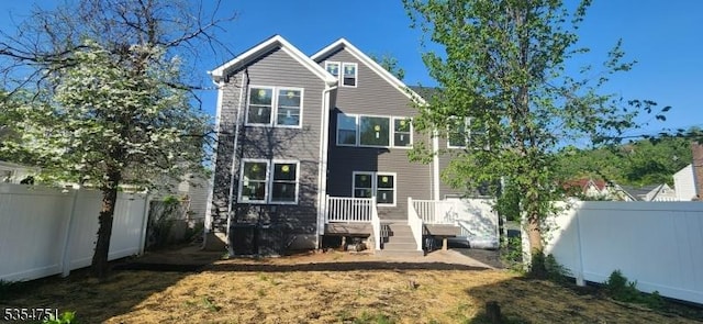 rear view of property with a fenced backyard and a deck