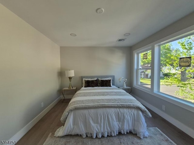 bedroom with baseboards, visible vents, and wood finished floors