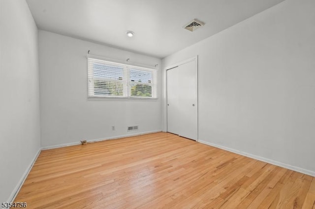 spare room featuring visible vents, baseboards, and wood finished floors