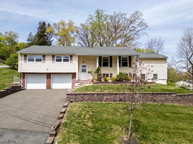 raised ranch with covered porch, an attached garage, a front lawn, and aphalt driveway