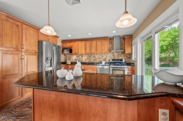 kitchen with backsplash, stainless steel appliances, brown cabinets, and wall chimney exhaust hood