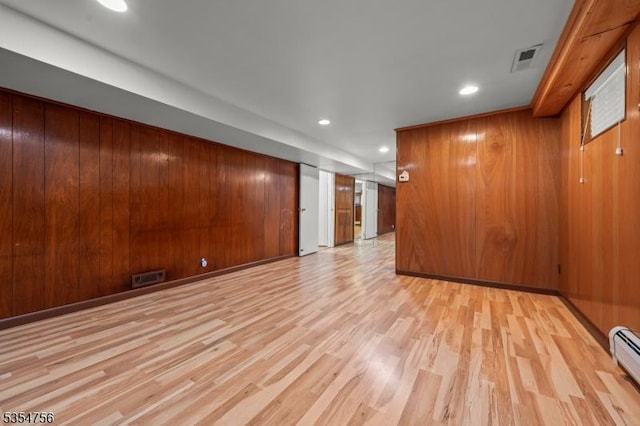 empty room featuring light wood-type flooring, recessed lighting, a baseboard heating unit, and visible vents
