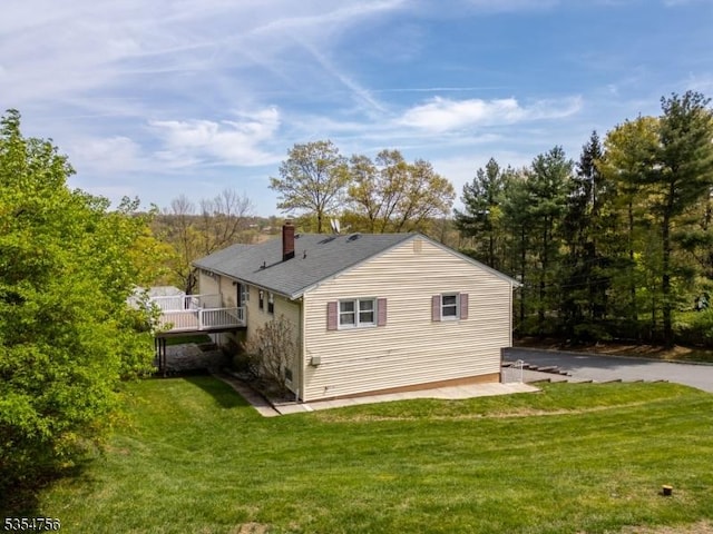 rear view of house with a wooden deck, a yard, and a chimney