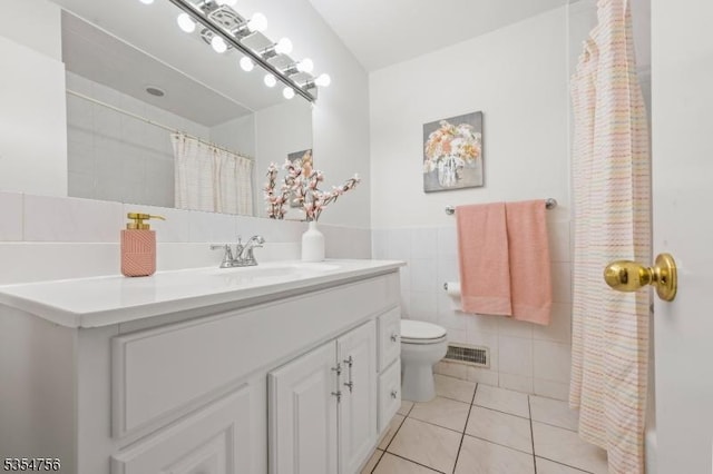 bathroom featuring visible vents, vanity, toilet, tile walls, and tile patterned floors
