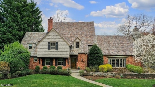 view of front of property with brick siding, a chimney, and a front lawn