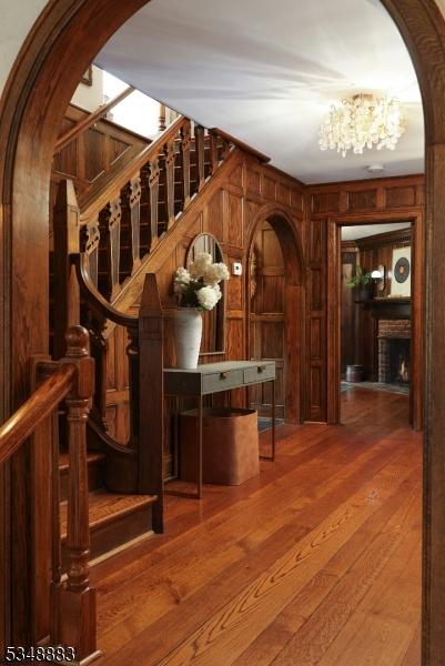 wine area with an inviting chandelier, arched walkways, wood walls, and hardwood / wood-style floors