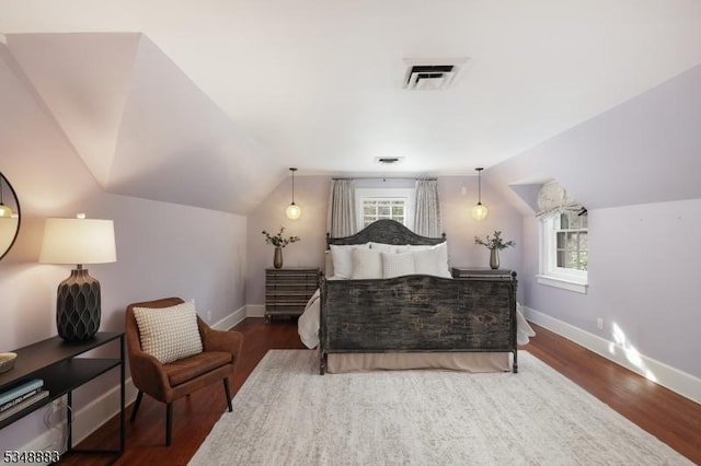 bedroom with baseboards, vaulted ceiling, wood finished floors, and visible vents