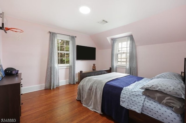 bedroom with baseboards, lofted ceiling, wood finished floors, and multiple windows