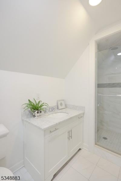 bathroom featuring baseboards, a sink, a stall shower, and vaulted ceiling