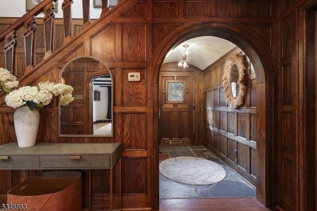 entryway featuring arched walkways and wood walls