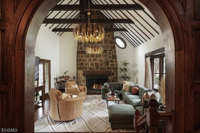 living room with an inviting chandelier, arched walkways, high vaulted ceiling, a wealth of natural light, and beamed ceiling