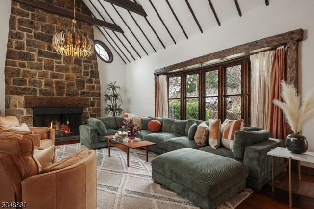 living room featuring high vaulted ceiling, a chandelier, a stone fireplace, wood finished floors, and beamed ceiling