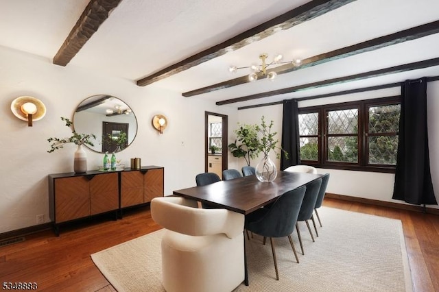 dining room featuring baseboards, wood finished floors, a notable chandelier, and beamed ceiling