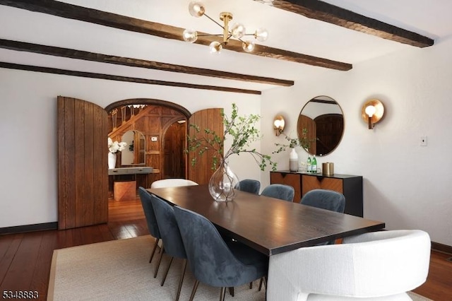 dining area featuring arched walkways, a notable chandelier, beam ceiling, and hardwood / wood-style floors