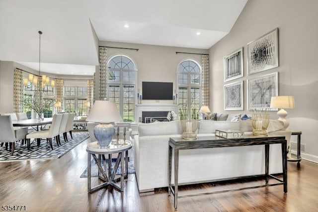 living area featuring baseboards, a fireplace, wood finished floors, and a notable chandelier