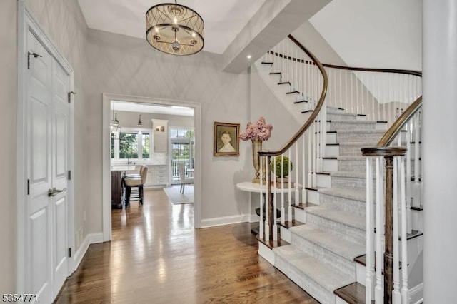 entryway with baseboards, stairs, wood finished floors, and a chandelier