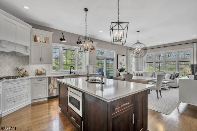 kitchen featuring dark brown cabinetry, appliances with stainless steel finishes, light countertops, a notable chandelier, and white cabinetry