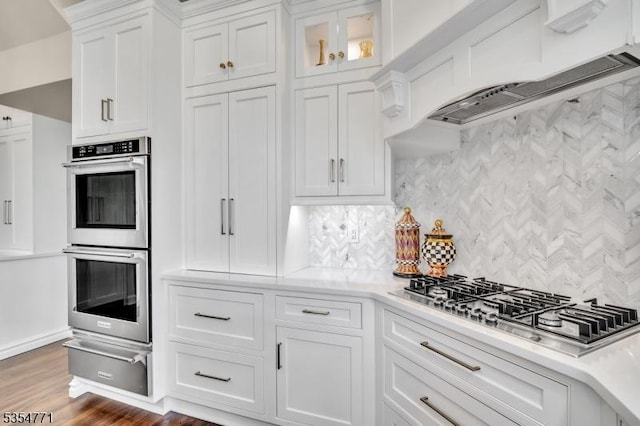 kitchen featuring white cabinets, light countertops, stainless steel appliances, decorative backsplash, and a warming drawer