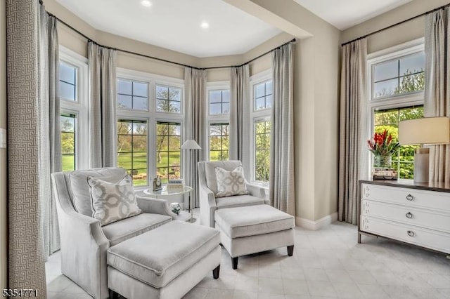 living area featuring baseboards, light tile patterned floors, and a healthy amount of sunlight