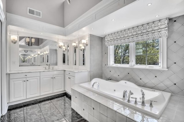 bathroom featuring an inviting chandelier, vanity, recessed lighting, a tub with jets, and visible vents