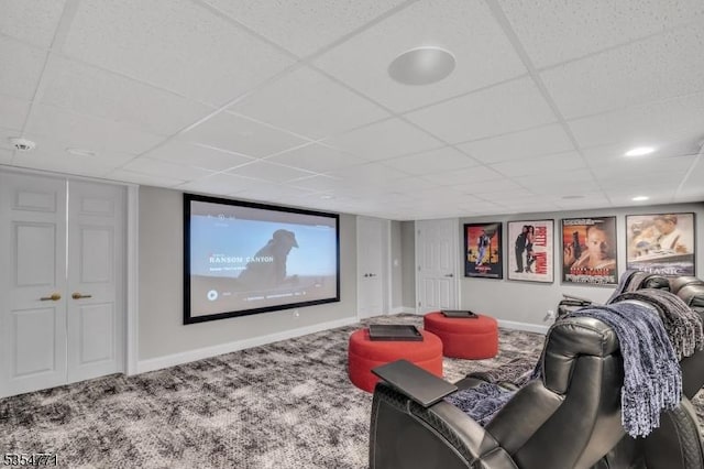 carpeted home theater featuring baseboards and a drop ceiling