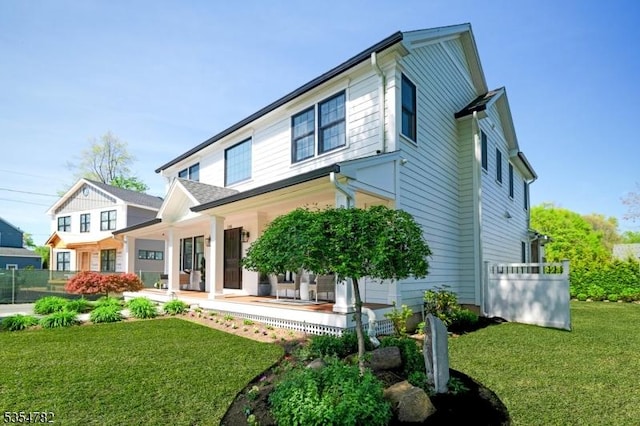 back of house featuring covered porch and a lawn