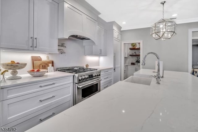 kitchen featuring stainless steel range, a sink, recessed lighting, decorative light fixtures, and custom range hood
