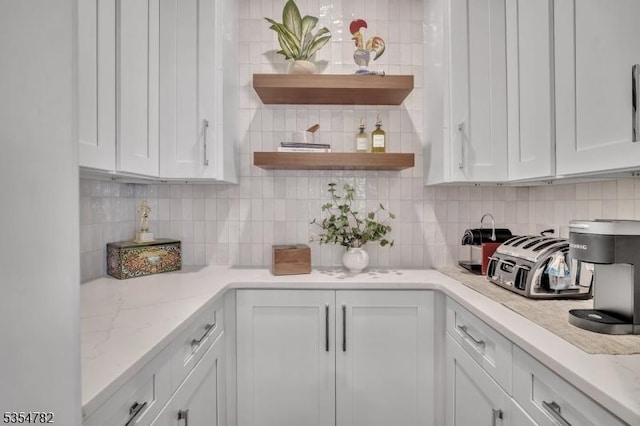 kitchen featuring decorative backsplash, white cabinets, open shelves, and light stone countertops