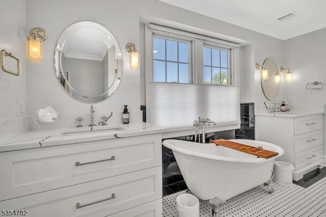full bathroom with visible vents, ornamental molding, a freestanding bath, two vanities, and a sink