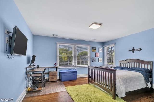 bedroom featuring baseboards, wood finished floors, and visible vents