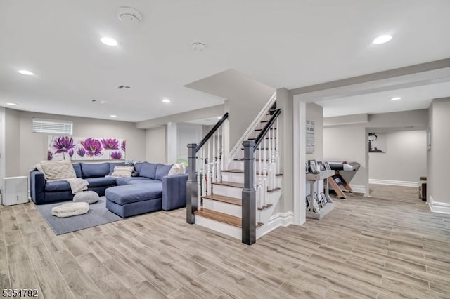 living room featuring light wood-style floors, baseboards, recessed lighting, and stairs
