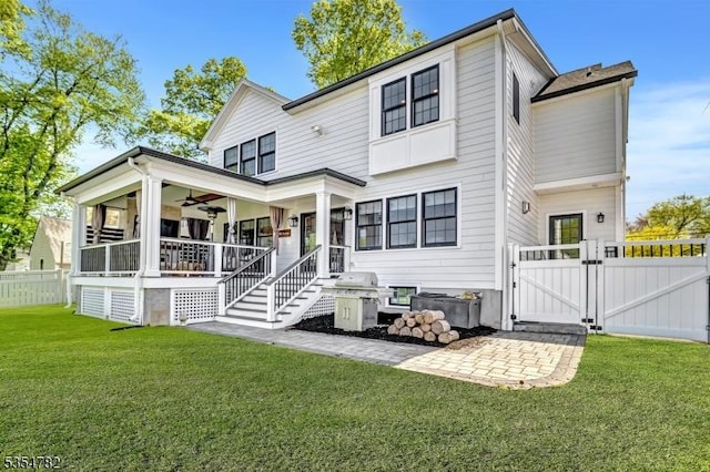 back of house with a porch, ceiling fan, a lawn, a gate, and fence