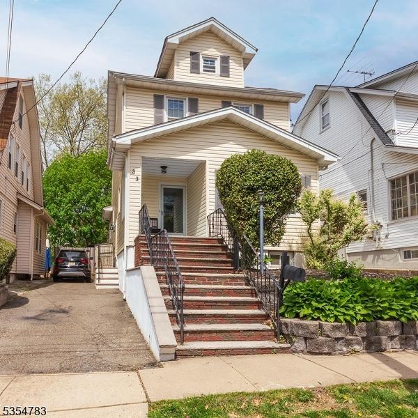 american foursquare style home with driveway, stairway, and covered porch