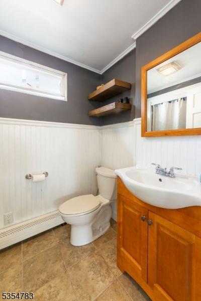 bathroom with vanity, ornamental molding, wainscoting, toilet, and a baseboard heating unit