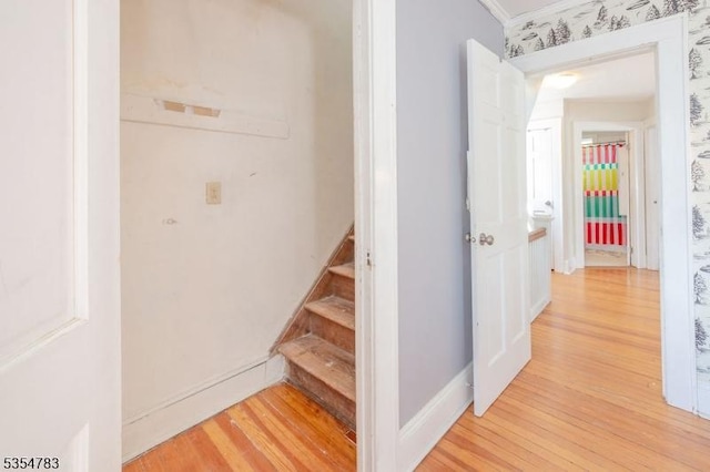 corridor with light wood-style floors, baseboards, ornamental molding, and stairs