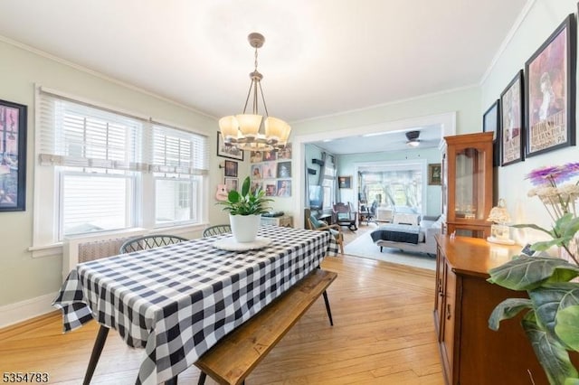 dining space featuring a notable chandelier, ornamental molding, a healthy amount of sunlight, and light wood-style flooring