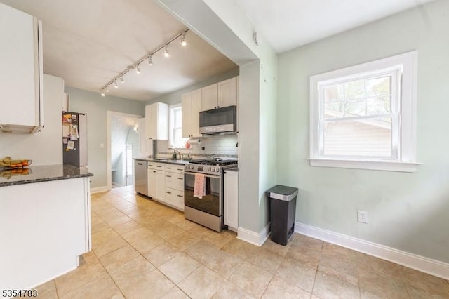 kitchen with track lighting, white cabinetry, tasteful backsplash, a sink, and stainless steel appliances