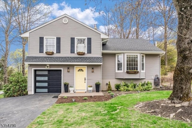 split level home with an attached garage, aphalt driveway, roof with shingles, and a front lawn